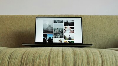 A laptop displaying black-and-white photos, set on a green surface.