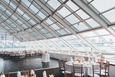 Modern wedding reception with rose gold chiavari chairs and white linens at the Adler Planetarium in Chicago during the day