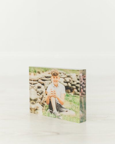 Portrait of a boy in an acrylic block by a white wall to display a product from a professional printing service.