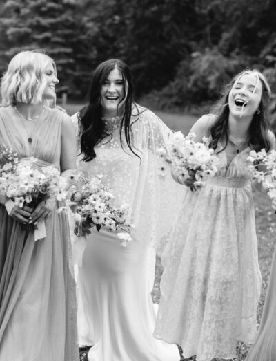 a bride with bridal cape laughs with bridesmaids at Glass House Community wedding venue, Michigan