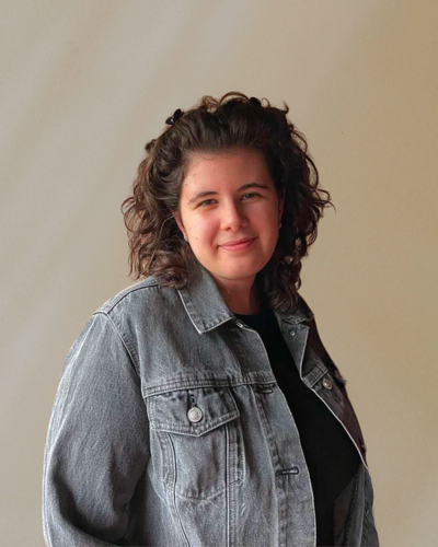 Portrait of Sofia Shepherd wearing a denim jacket and smiling, set against a neutral background. Founder of The Cosmic Lab, specializing in brand and web design.