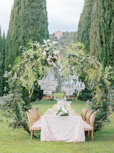 intricate tablescape with detailed, greenery-adorned wreath around tablescape with chandeliers at villa cetinale in tuscany, italy