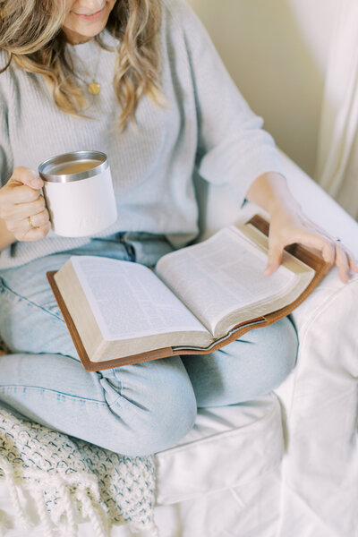 woman holding coffee reading her Bible
