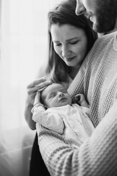 Eine Mutter liegt neben ihre Newborn und guckt liebevoll an.