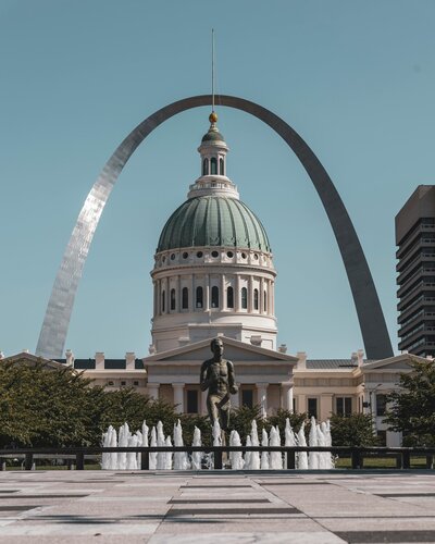 fountain feature in front of the state capitol on a sunny day, the gateway arch in the background on blue sky