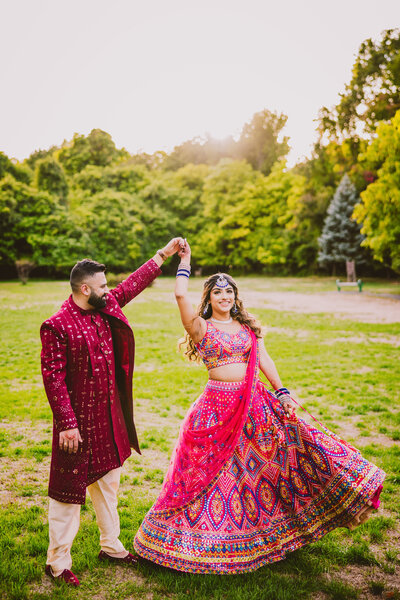 A groom twirling the bride at a park in nj in indian outfits before their sangeet garba