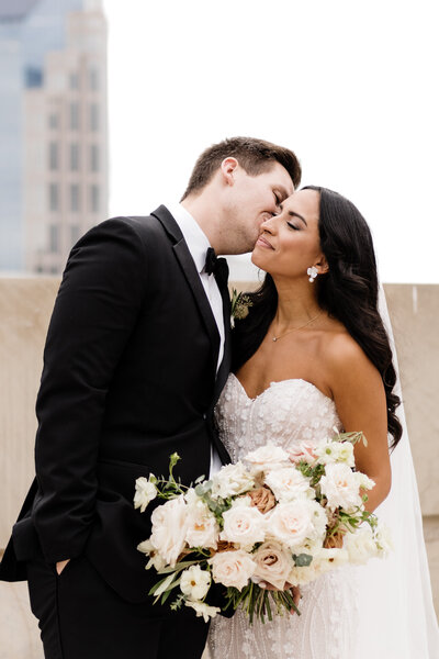 groom kissing bride on the cheek in front of nashville skyline