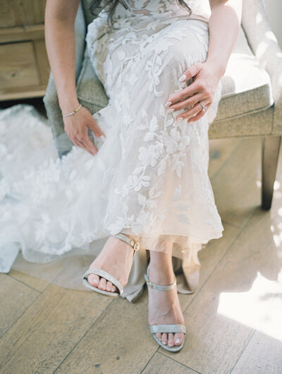 A bride in a wedding dress sitting on a chair.
