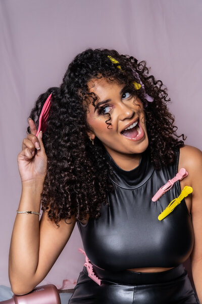 Woman with curly hair smiling with her eyes closed, with hairpins in her hair