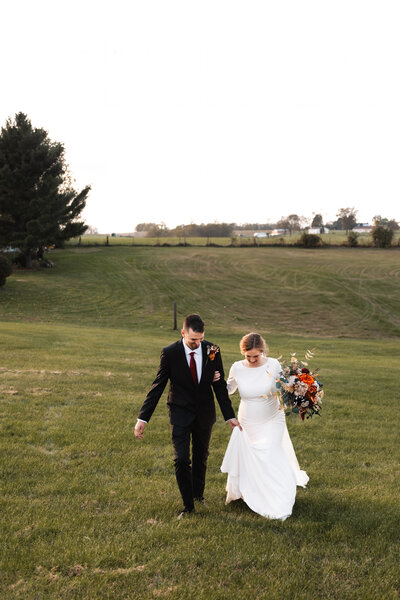 Bride and groom walking hand in hand toward the camera on their wedding day, capturing joyful, candid movement.