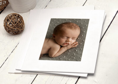 matted print of a newborn  baby   boy on white  wood table