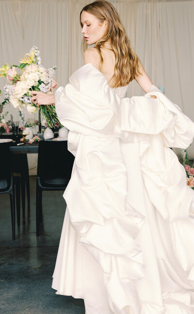 Woman wearing a large ruffled wedding dress and holding a bouquet