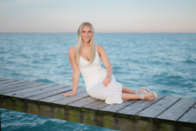Senior photoshoot on a beach dock with the water in the background.