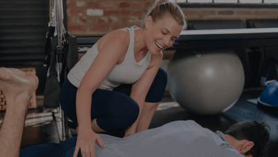 woman assisting a student in a pilates class 