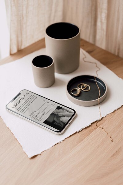 Luxury Showit website template for wedding photographers shown on mobile, highlighting service experience options like weddings, elopements, and engagements. Elegant flatlay with gold rings and minimal styling—ideal inspiration for photographers seeking timeless website design ideas.