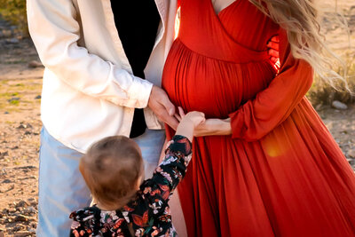 arizona mom with two daughters hugging her maternity belly in lake pleasant for photography session