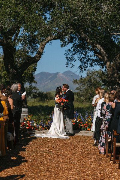 Wedding ceremony under oaks with mountains in the background in California