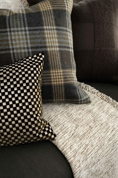 A cozy couch adorned with three soft pillows and a warm blanket, inviting relaxation and comfort.