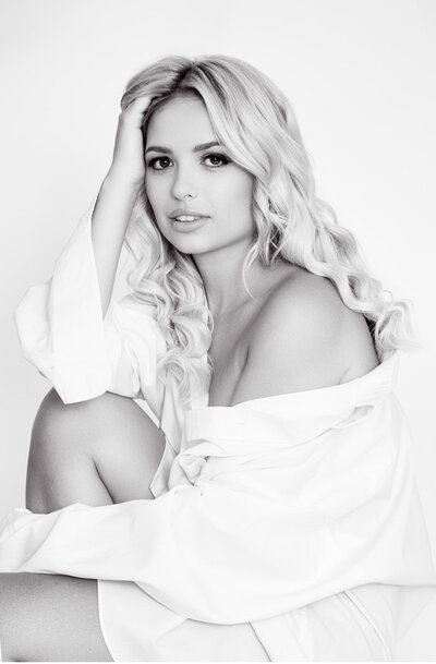 Explore the captivating debut of a first-time model in this striking black and white portrait by I-CanDee Photography. The image features the model gracefully posing in an oversized white shirt, demonstrating a surprising level of confidence and style for a newcomer. Captured in Charlotte, NC, this photo highlights the elegance of monochrome photography and the model’s natural allure. I-CanDee Photography excels in creating memorable and professional portraits, showcasing the unique beauty of each subject.