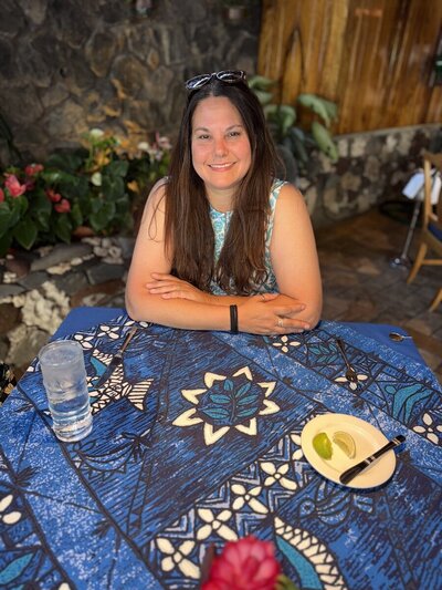 Woman with brown hair and sunglasses on the top of her head smiling at the camera