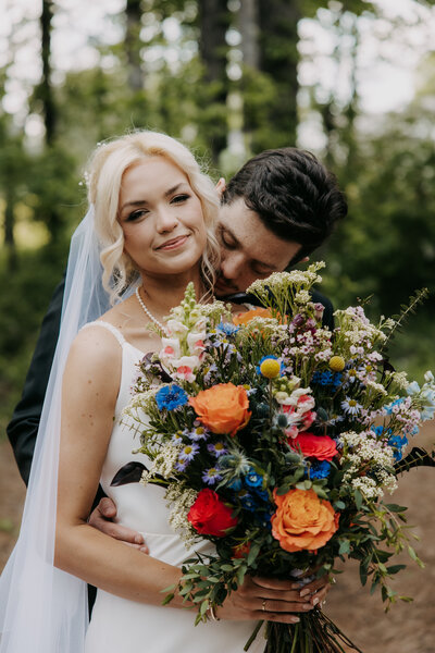 Yana and Brian embracing during their bridal portraits in the trees after their wedding ceremony at Kincaid Manor, sharing a tender moment.