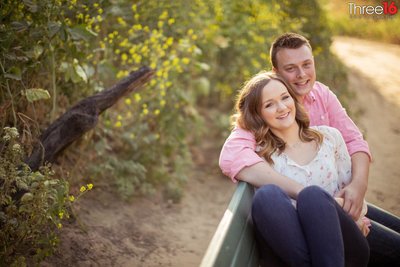 Groom to be embraces his Bride during an engagement photo session in the open field of Carbon Canyon Regional Park in Brea, CA