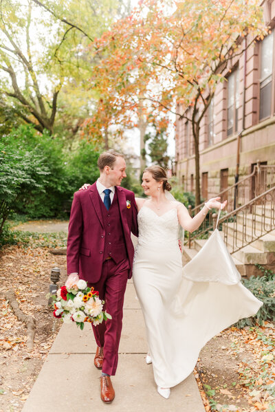 A bride and groom walking down a sidewalk together.
