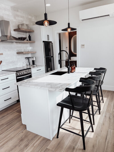 Kitchen with white cabinets with grey counters and black chairs