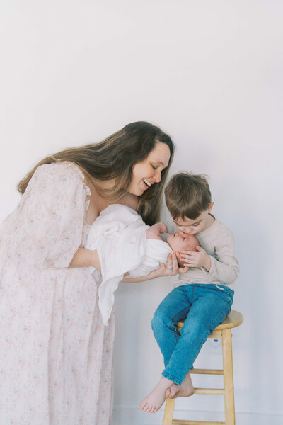a mom and toddler smiling at a newborn baby