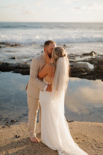 bridge and groom kisisng on beach in kauai