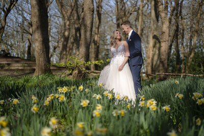Bruidspaar kijkt elkaar romantisch in de ogen in het bos van Texel  tussen de bloemen