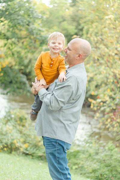 a father holding his toddler near a river