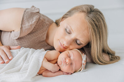mother laying her cheek on sleeping newborn