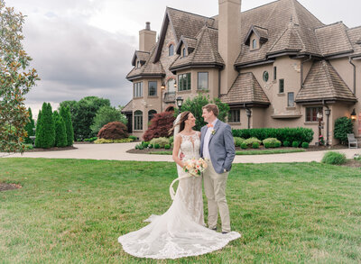 bride and groom looking at each other standing in front of large home