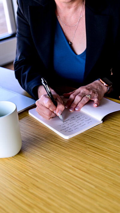 alt="Close-up of Jennifer Petersen's hands writing notes wearing a blue top, with 'EMPLOYMENT LAW' text overlay in burgundy"