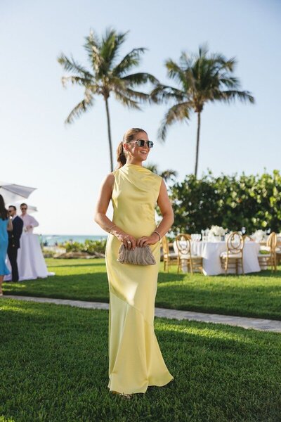 wedding guest wearing yellow and posing by wedding photographers in naples
