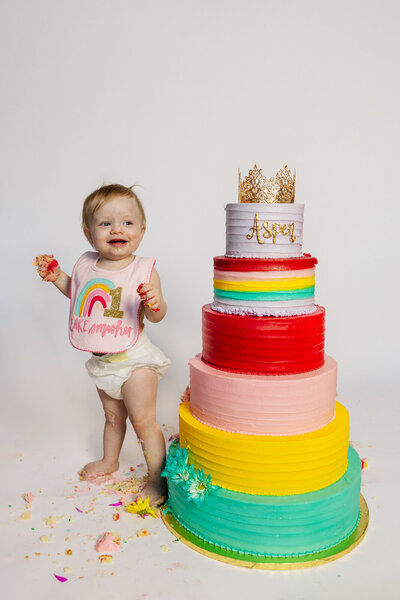 Baby stands next to 6 tier cake for cake smash in Dacula, Georgia