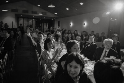 Black and white photo of wedding guests sitting at a long reception table