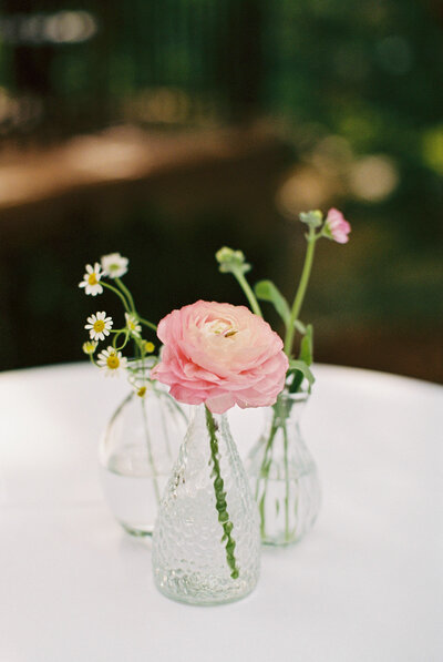 white table with clear vases of little flowers
