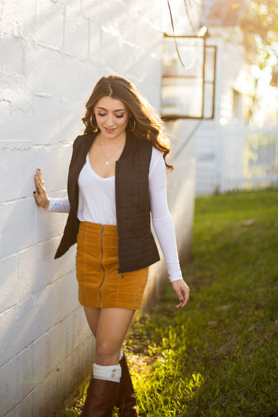 Teen girl walks along a white wall in the sunshine