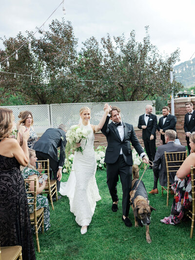 Bride and groom walk down the aisle with their dog after their wedding ceremony, at St, Julien in Boulder, Colorado