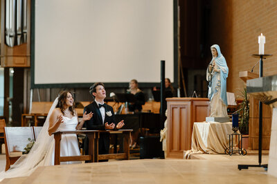 a bride and groom singing praise and worship during their wedding mass