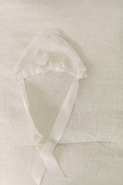 baby bonnet  on bed for baptism in Oakville ON