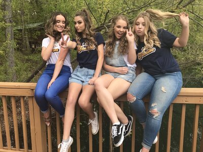 girls sitting on a railing smiling