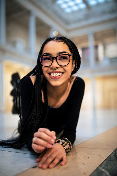 She image of a dark skin girl with braids posing for senior portraits inside of the Pittsburgh Field museum