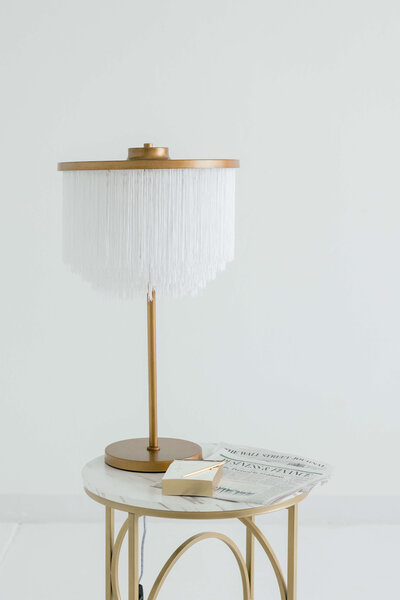 White and gold lamp on a gold and marble table