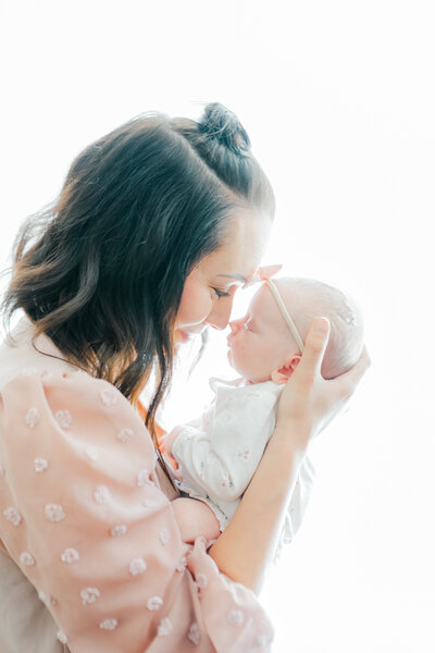 Mother holding newborn baby close to her face nose to nose by Oklahoma City Newborn Photographer Courtney Cronin