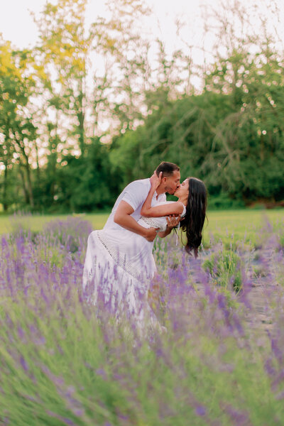 A person dipping their partner and kissing them in a field of purple flowers 