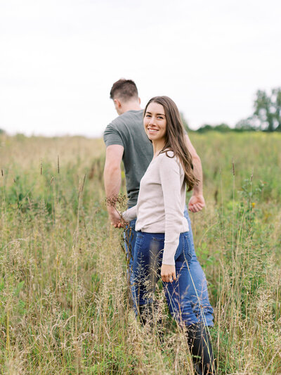 Couple walks through field in their nature preserve  engagement session in Cleveland