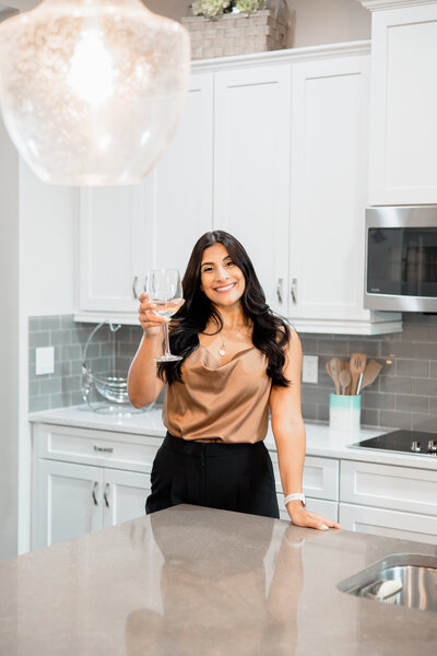 Lakeland Florida realtor cheers with wine glass to camera standing in modern kitchen